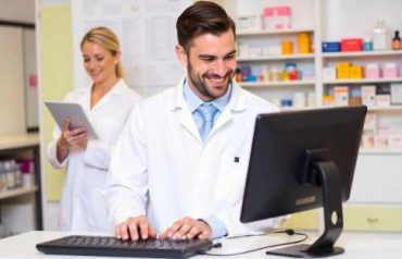 Pharmacist using pharmacy management software on desktop computer